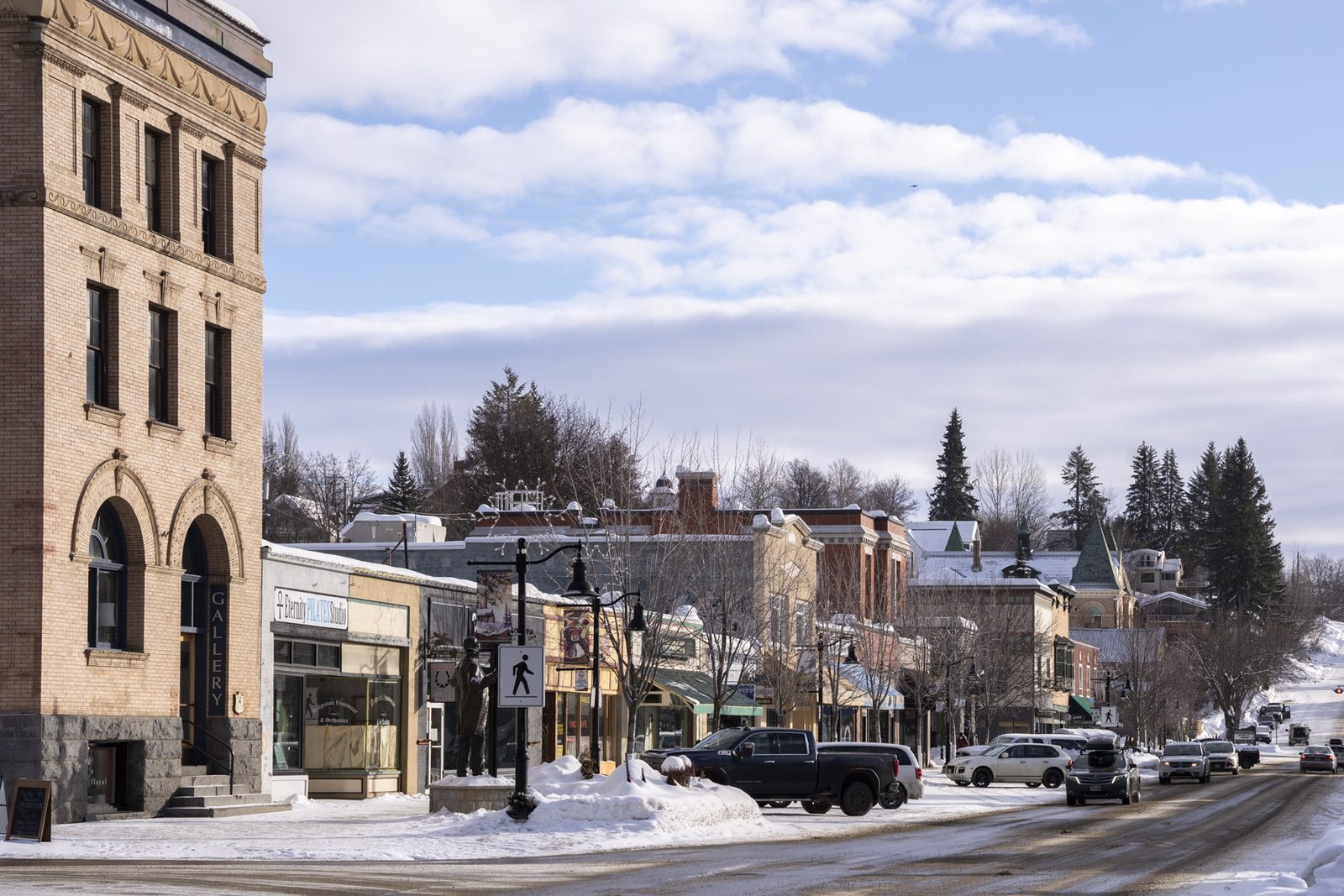 Historic brick and stone heritage buildings lining a snowy main street in downtown Rossland, BC, survivors of the gold-rush boomtown era